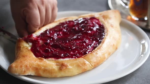 Baker cuts freshly baked sweet jam pie into portions
