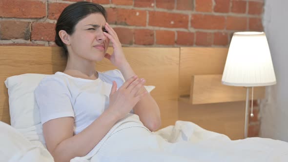 Young Indian Woman Feeling Worried while Sitting in Bed alt