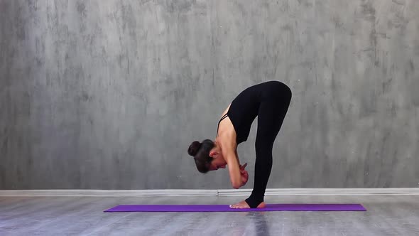 Woman in Sports Black Clothes is Engaged in Yoga on Purple Rug in Studio with Natural Consecration alt