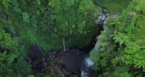 circling downward drone footage of the kedung kayang waterfall in indonesia with the surrounding pla alt