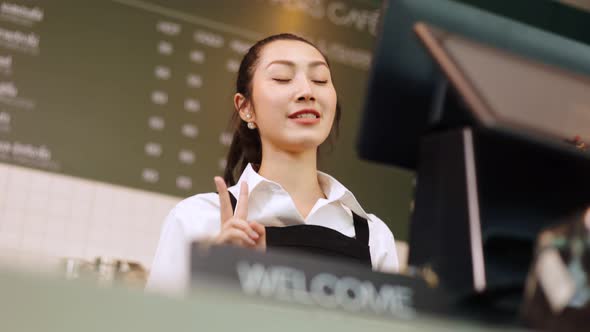 Portrait young Asian woman barista feeling happy smiling at urban cafe. alt