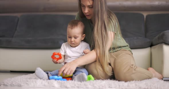 Happy Young Mother and Child Boy Play Together with Pyramid Indoors at Home alt