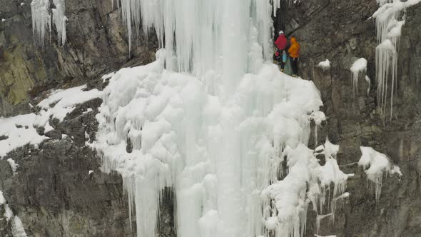 Climbers resting on ledge of frozen cascade ice climbing Maineline, Kineo Mount alt