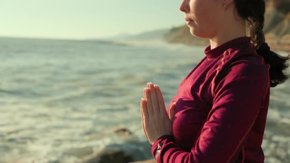 A stressed woman meditates on the seashore.The sea surf is in the background. alt