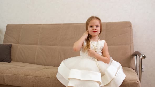 A Young Blonde Little Girl Corrects Her Hair is Embarrassed and Smiles alt