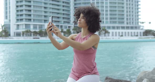 Cheerful Black Woman Taking Selfie on Seafront alt