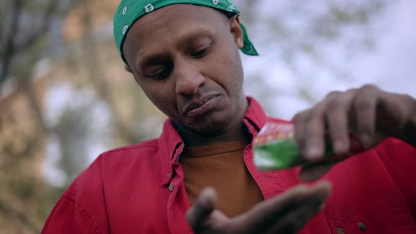Closeup Portrait of Concentrated African American Gardener Pouring Seeds From Package in Hand alt