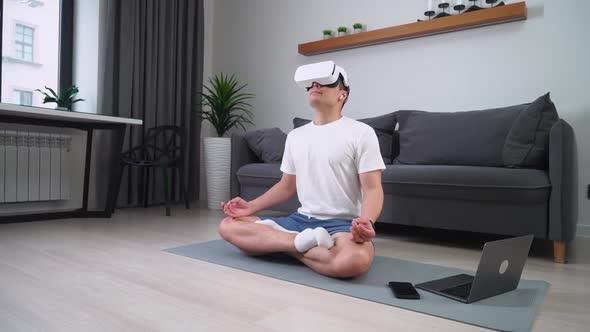 Cheerful Man in Virtual Reality Glasses Meditates in the Living Room Modern Technology and Augmented alt