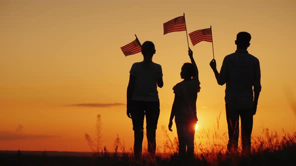 Family with Child Waving US Flags at Sunset, Rear View alt