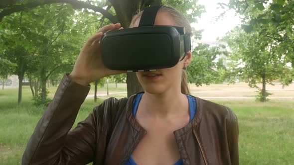 Beautiful Cheerful Girl Uses A Modern Virtual Reality Helmet In The Park