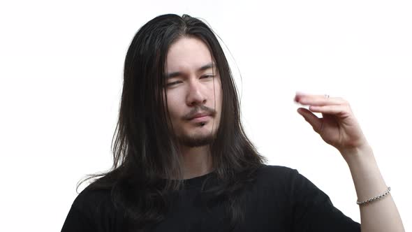 Closeup of Handsome Eastasian Bearded Guy with Long Dark Hair and Piercing Looking Tired and Showing alt
