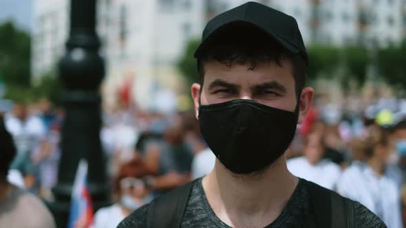 Portrait of Anonymous Protester in Coronavirus Face Mask Standing in Crowd March alt