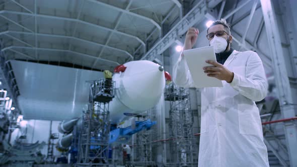 Adult Engineer of Industry Four in Face Mask Working in Large Space Production alt