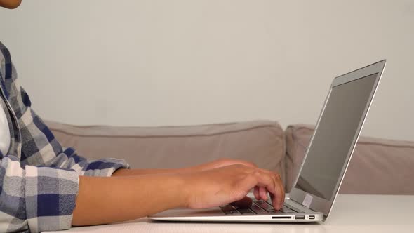 A AfricanAmerican Woman is Typing on a Laptop Keyboard While Sitting at Home