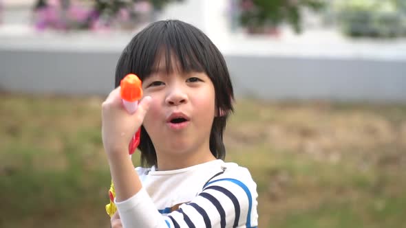Cute Asian Child Playing With Water Gun In The Summer4 alt