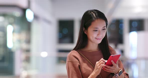Woman check on the discount in mobile phone inside shopping plaza alt