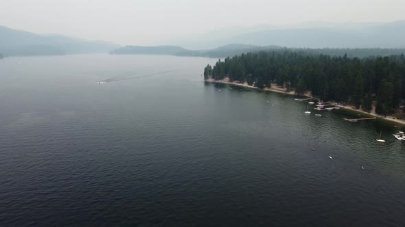Counterclockwise drone shot of the shore and water at Lake Payette in McCall, Idaho on a very smoky alt