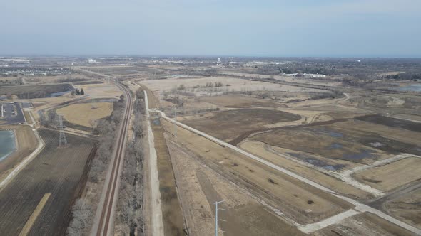 Aerial view of rural landscape including railroad tracks, farm fields and transmission towers.