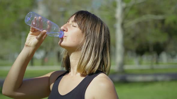 Beautiful Young Woman Drinking Water From Plastic Bottle alt