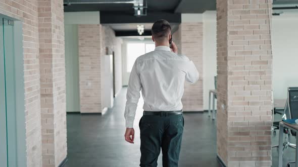 Rear Businessman Man Walks and Talks Use Smartphone
