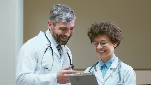 Two doctors with tablet computer joking