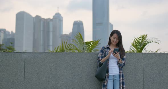 Woman look at mobile phone in city alt