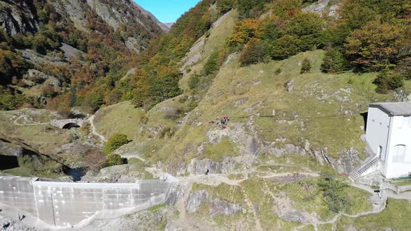 Lac d'Oô artificial lake in the French Pyrenees with hikers on the dam wall and man walking dog, Aer alt
