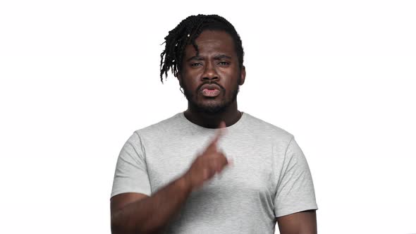 Portrait of Severe Bearded Dark Skinned Guy in Casual Tshirt with Strict Gaze Asking to Keep Quiet alt
