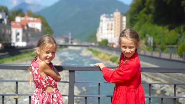 Back View of Girls on the Embankment of a Mountain River in a European City alt