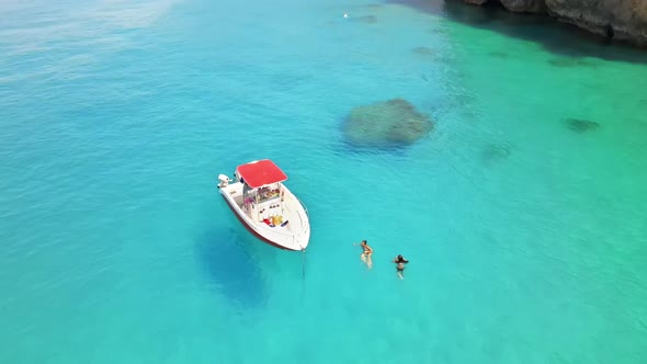 Aerial drone view of a moored boat near the coast of Zakynthos, Greece. Two women swimming alt