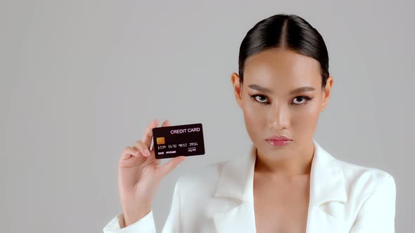 Beautiful Asian businesswoman showing credit card and looking at camera alt