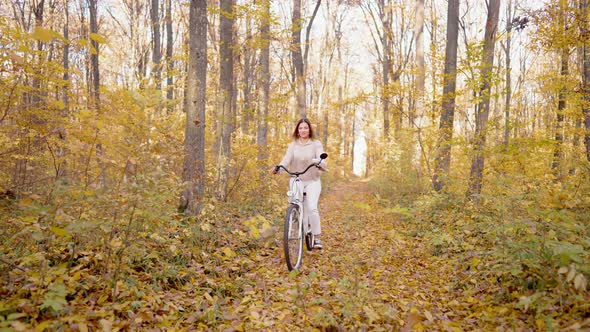 Beautiful Portrait of Young Woman Cycling Alone in Autumn Park alt