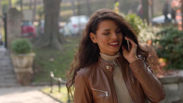 Pretty young woman with mobile phone on autumn day