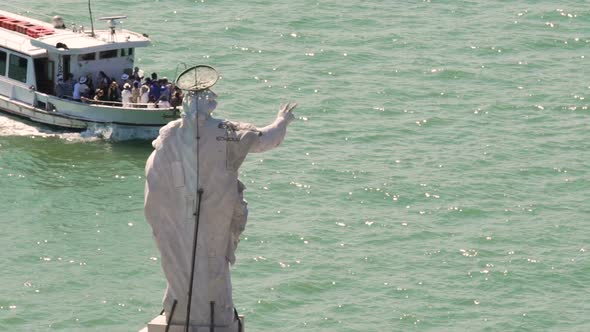 Tourist ferry going across river passing statue of a saint, sightseeing tour alt