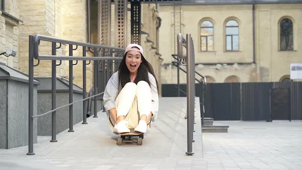 Woman having fun, sitting on the skateboard. 