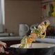 Woman Tossing Vegetables On A Frying Pan In The Kitchen In Slow Motion Shot On Red Camera - VideoHive Item for Sale