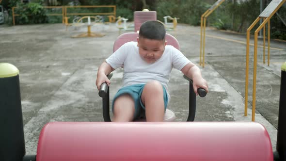 Happy Little asian boy playing exercise equipment in the outdoors,
