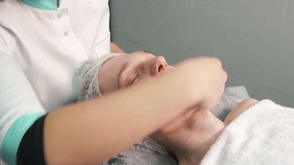 The Hands of a Cosmetologist Clean the Face of a Young Man with Cotton Pads