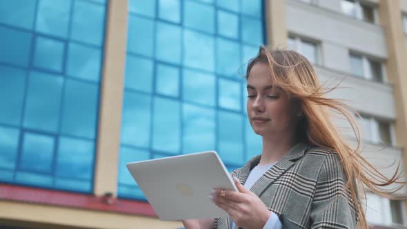 A Young Girl Student Works with a White Tablet in the City alt