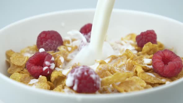 Pouring Milk On Cereals With Raspberry