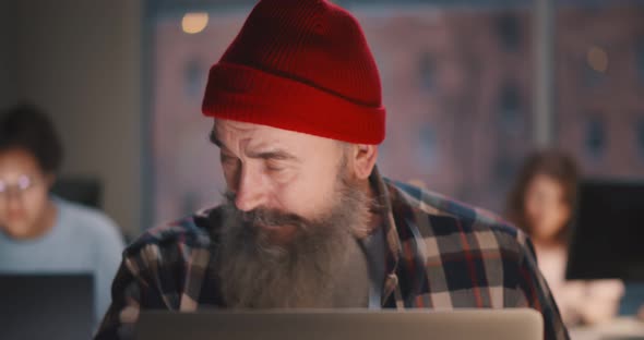 Senior Man in Stylish Outfit Feeling Stressed Working on Laptop Late at Night in Office alt