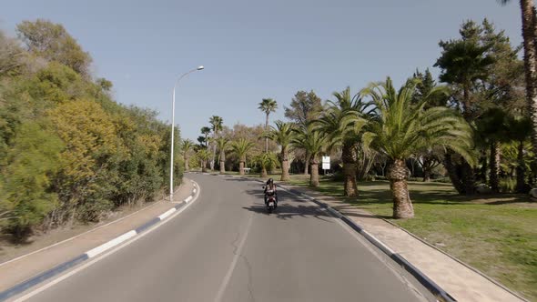 Wide aerial of a couple riding on motorbike in Marbella in summertime alt