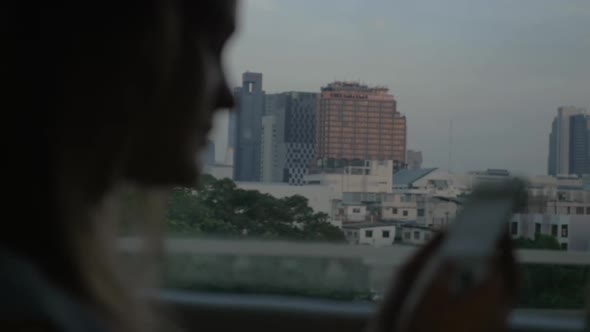 Woman with cell going by bus in Bangkok, Thailand alt