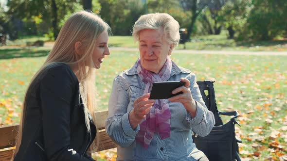 Elder Grandmother Showing Her Granddaughter Photos on Smartphone alt