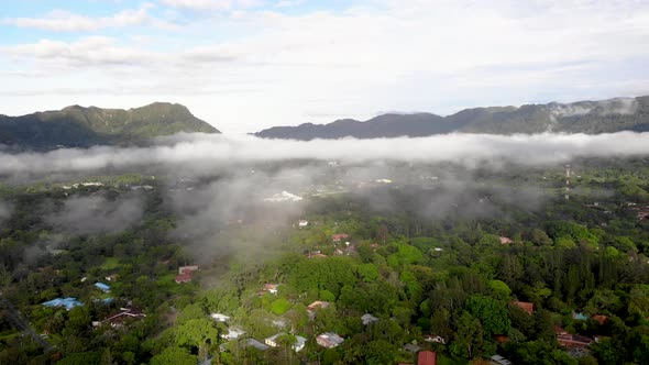 Lower clouds over homes in Valle de Anton town in central Panama extinct volcano crater, Aerial pan alt