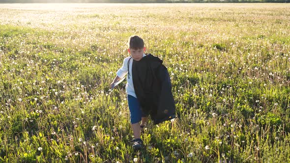 A Boy Walks Across a Field with a Sword in His Hands
