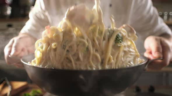 chef in modern kitchen mixes ingredients in wok. close up alt