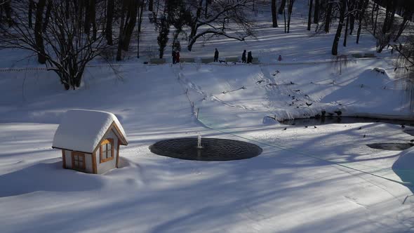 Fountain on a frozen lake in a winter park. alt