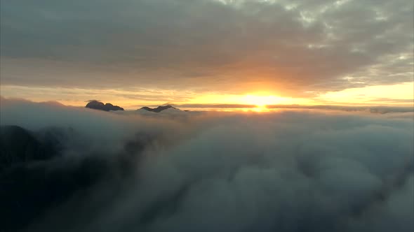 Flying towards midnight sun above the clouds alt