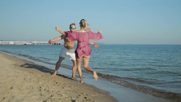 Cheerful reunion hug and kiss on the beach for two young lovers alt